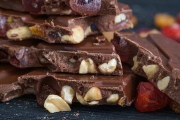 Milk chocolate with nuts, raisins, sec fruits. Close up, selective focus.