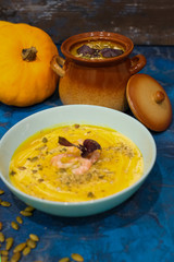 pumpkin soup with cream and shrimp, decorated with pumpkin seeds