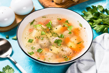 Meatballs soup with vegetables on blue.
