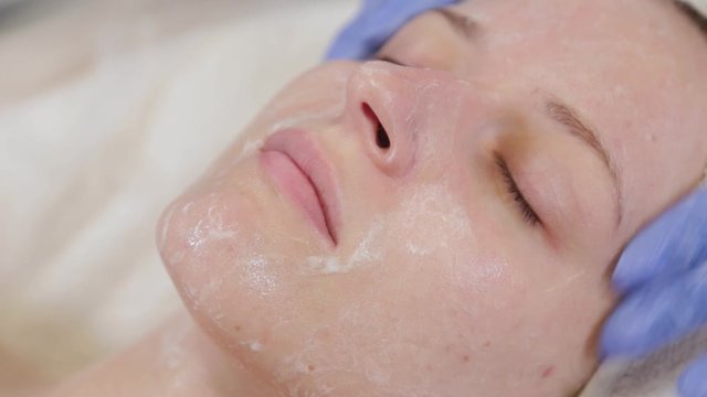 Professional beautician washes a woman and massages her face.