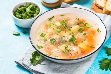 Meatballs soup with vegetables on blue.