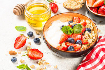 Greek yogurt granola with fresh berries on white stone table.