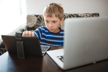 Young boy plays on the tablet and laptop