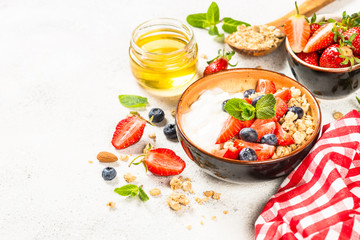 Greek yogurt granola with fresh berries on white stone table.