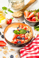 Greek yogurt granola with fresh berries on white stone table.