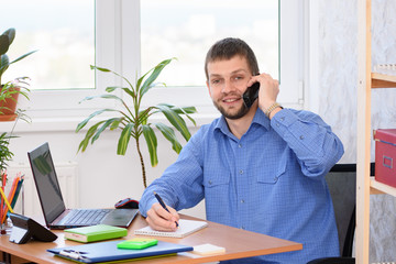 Fototapeta premium An office employee is talking on the phone with a smile and looked in frame