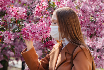 A young girl takes off her mask and breathes deeply after the end of the pandemic on a Sunny spring...