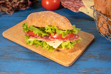 Sandwich with salami and cheese on wooden background