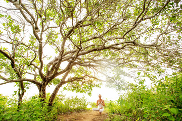 Woman practicing yoga at sunset