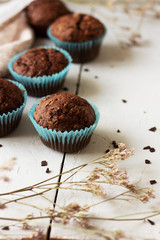 Homemade сhocolate muffins with banana in blue paper cups  on white, wooden background.