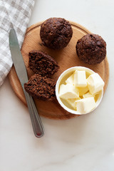 Homemade сhocolate muffins with banana and butter on a wooden background.Top view.