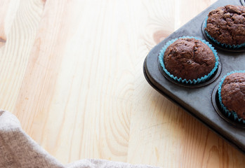 Homemade сhocolate muffins with banana in a baking form on a wooden background.