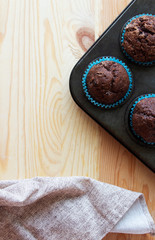 Homemade сhocolate muffins with banana in a baking form on a wooden background. Top view.