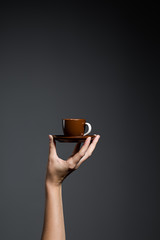 Hand holding a cup of coffee on grey background