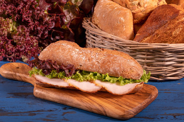 sandwich with salami and salad on wooden background
