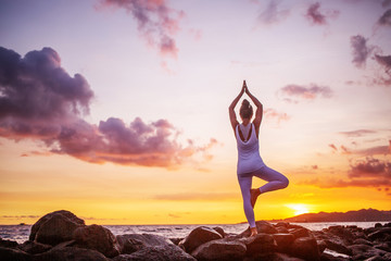 Woman practices yoga at seashore
