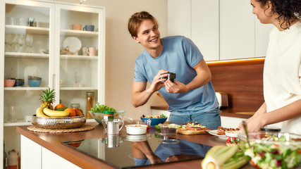 Cookery school. Cheerful couple recording video blog about vegetarian healthy food on camera in the...