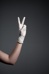 Hand in protective glove making peace gesture
