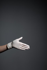 Womans hand in white protective gloves on gray background