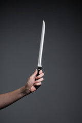 Hand holding a knife on grey background