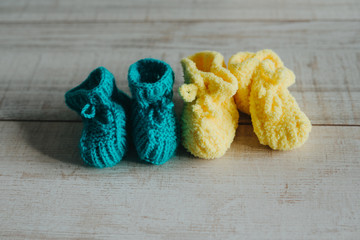 Fototapeta na wymiar Yellow and mint knitted booties on the wooden floor.