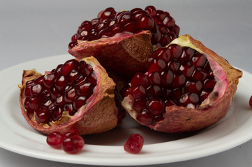 Pieces of pomegranate on a white plate and a white background.