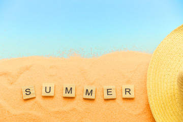 Summer holidays background, sand, hat, the word of the Summer. Concept of a summer vacation on the beach with a blue copy of the space