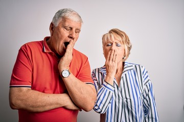 Senior beautiful couple standing together over isolated white background bored yawning tired...