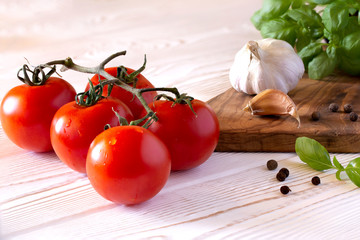 Fresh tomatoes with basil, garlic and spices on a wooden white table in rustic style. Copy space