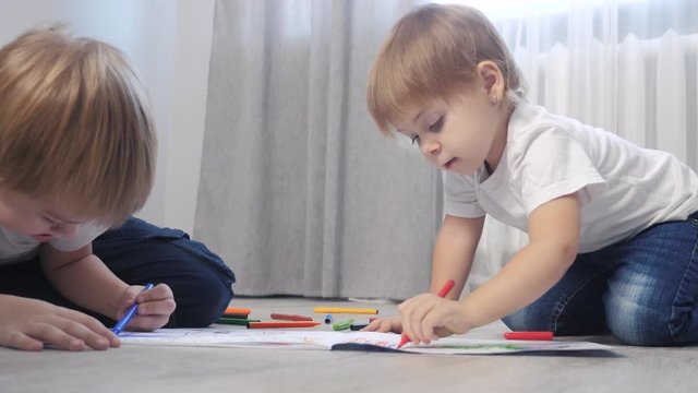 children draw with felt-tip pens in an album. little boy and girl concept childhood brother and sister play paint on floor with colored lifestyle markers