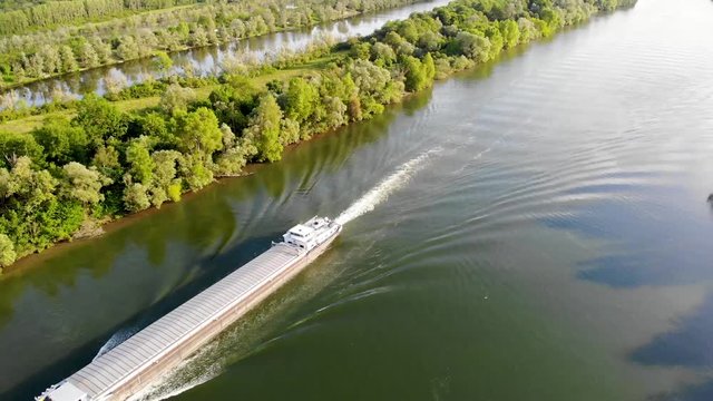 Scenic aerial view of the Seine river with boats and cargo barges and green fields in French countryside. Val d'Oise department, Ile-de-France, Northern France