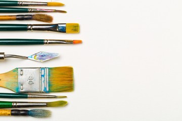 Artistic art supply utensils with brushes on white background with copy space flat lay top view...