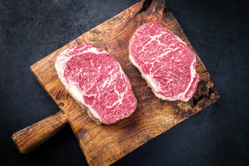 Raw dry aged wagyu entrecote beef steak roast as top view on a rustic wooden cutting board