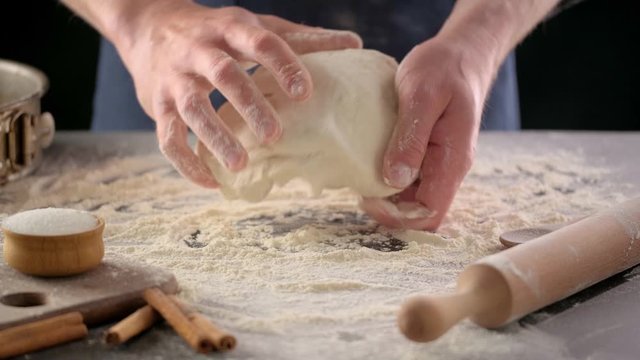 Baker hands are making dough with flour. Chef knead dough on kitchen table. Process preparation homemade pastry.