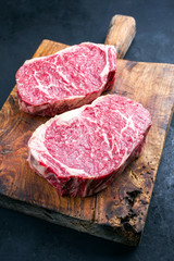 Rohes dry aged Wagyu Entrecote Steak vom Rind als closeup auf einem rustikalen Holz Schneidebrett 