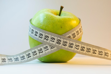 Green apple with measuring tape isolated on white background
