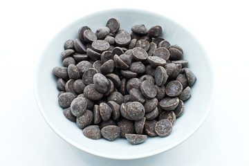 Small dark chocolate morsels in a white bowl