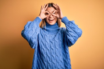 Young beautiful blonde woman wearing turtleneck sweater over yellow isolated background doing ok...