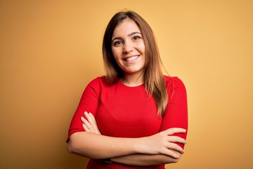 Obraz premium Beautiful young woman wearing casual red t-shirt over yellow isolated background happy face smiling with crossed arms looking at the camera. Positive person.