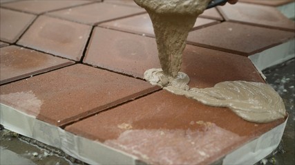 Filling paving slabs with a solution on the street. The builder fills the seams between the paving slabs.