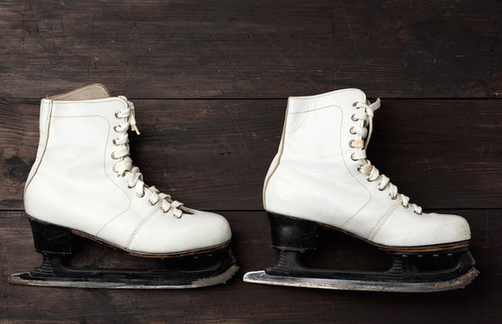 Pair Of White Leather Skates For Figure Skating On A Brown Wooden Background