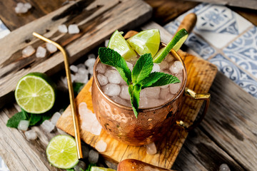 Cocktail de mojito en una taza de cobre y una pajita reutilizable, con ingredientes: lima, menta y hielo