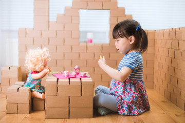 toddler girl pretend play baby care in a carton house