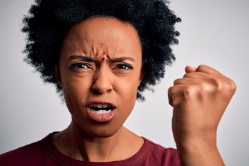 Young beautiful African American afro woman with curly hair standing over white background annoyed and frustrated shouting with anger, crazy and yelling with raised hand, anger concept