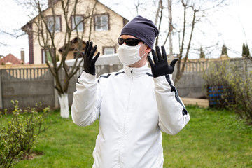 COVID-19. Man in white mask, sunglasses and black gloves in the backyard. Coronavirus in Europe. Pandemic life.