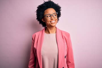Young beautiful African American afro businesswoman with curly hair wearing pink jacket smiling...