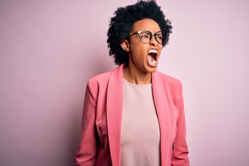 Fototapeta na wymiar Young beautiful African American afro businesswoman with curly hair wearing pink jacket angry and mad screaming frustrated and furious, shouting with anger. Rage and aggressive concept.