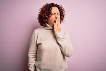 Middle age beautiful curly hair woman wearing casual turtleneck sweater over pink background bored yawning tired covering mouth with hand. Restless and sleepiness.
