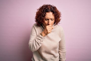 Fototapeta na wymiar Middle age beautiful curly hair woman wearing casual turtleneck sweater over pink background feeling unwell and coughing as symptom for cold or bronchitis. Health care concept.
