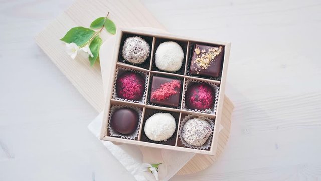 Handmade chocolate box candies in packaging on a white background with white flowers. Holiday sweet birthday, wedding, Valentine's Day gift